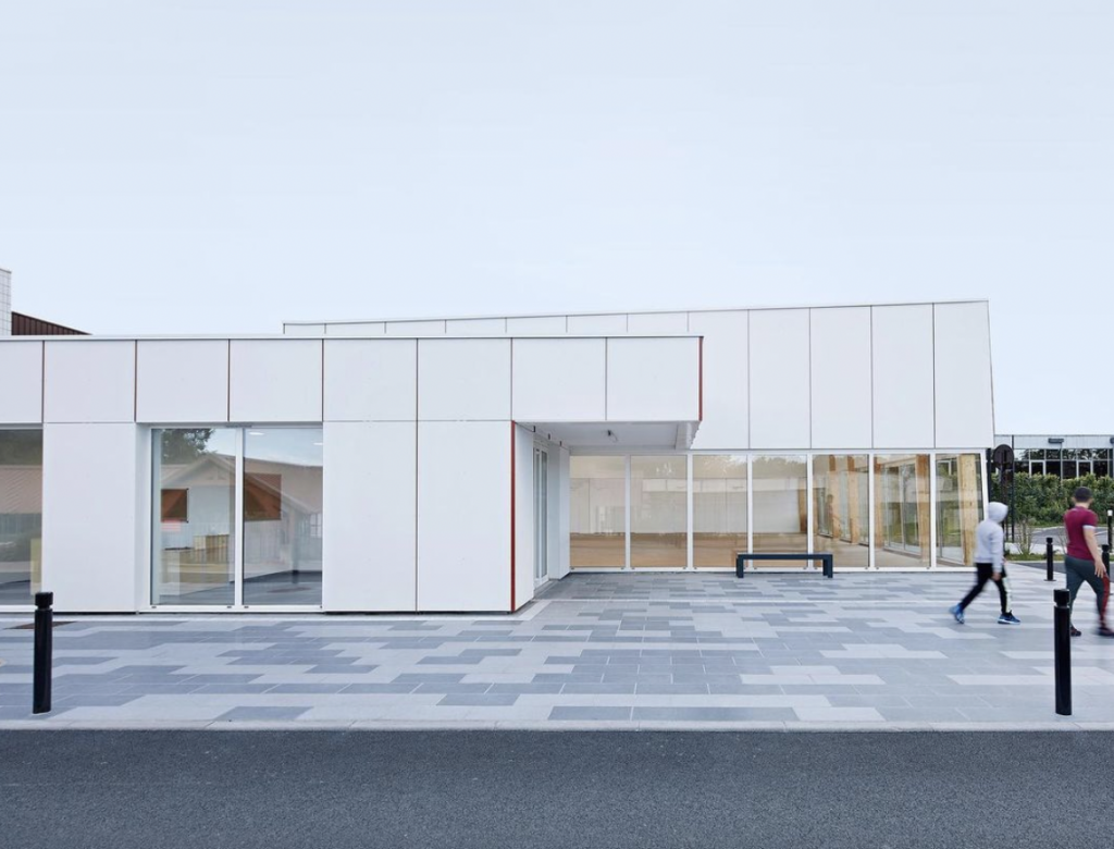 Hempcrete: The exterior of a sports hall in paris clad in white. Its a low square building 