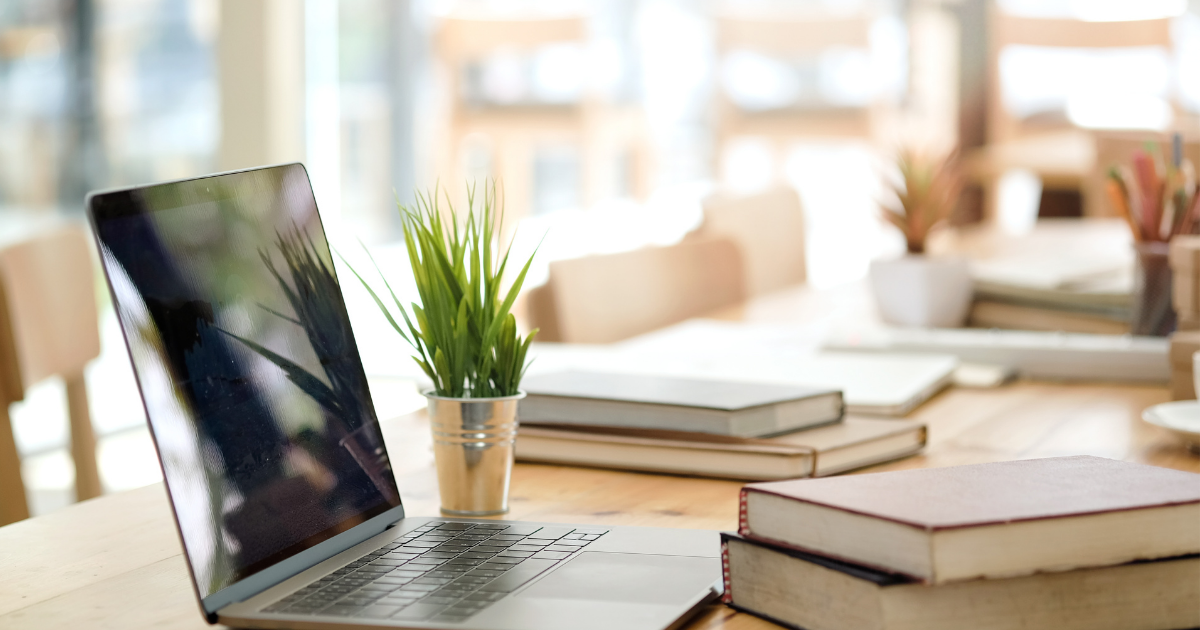 Remote working: A table with a laptop and a plant on it with books in the background