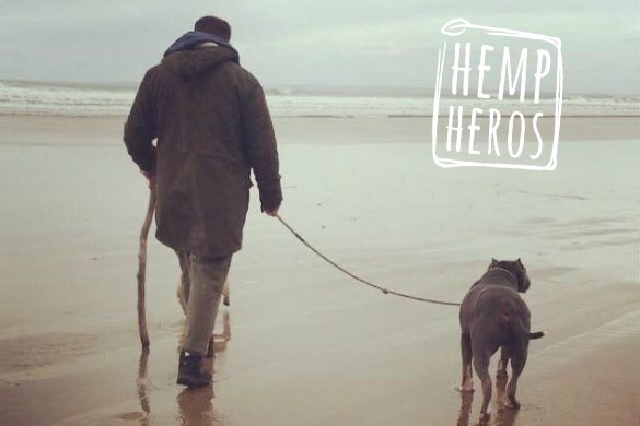 Welsh: A man walking a dog on a lead across a beach