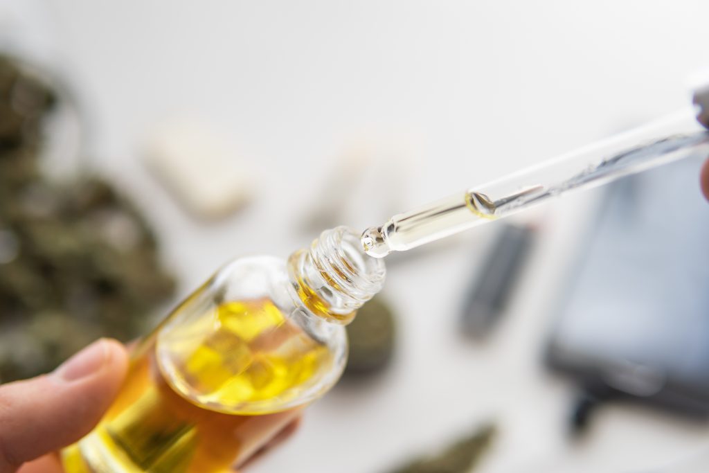 Fibromyalgia: A cbd oil bottle containing yellow oil has a dropper being placed into it