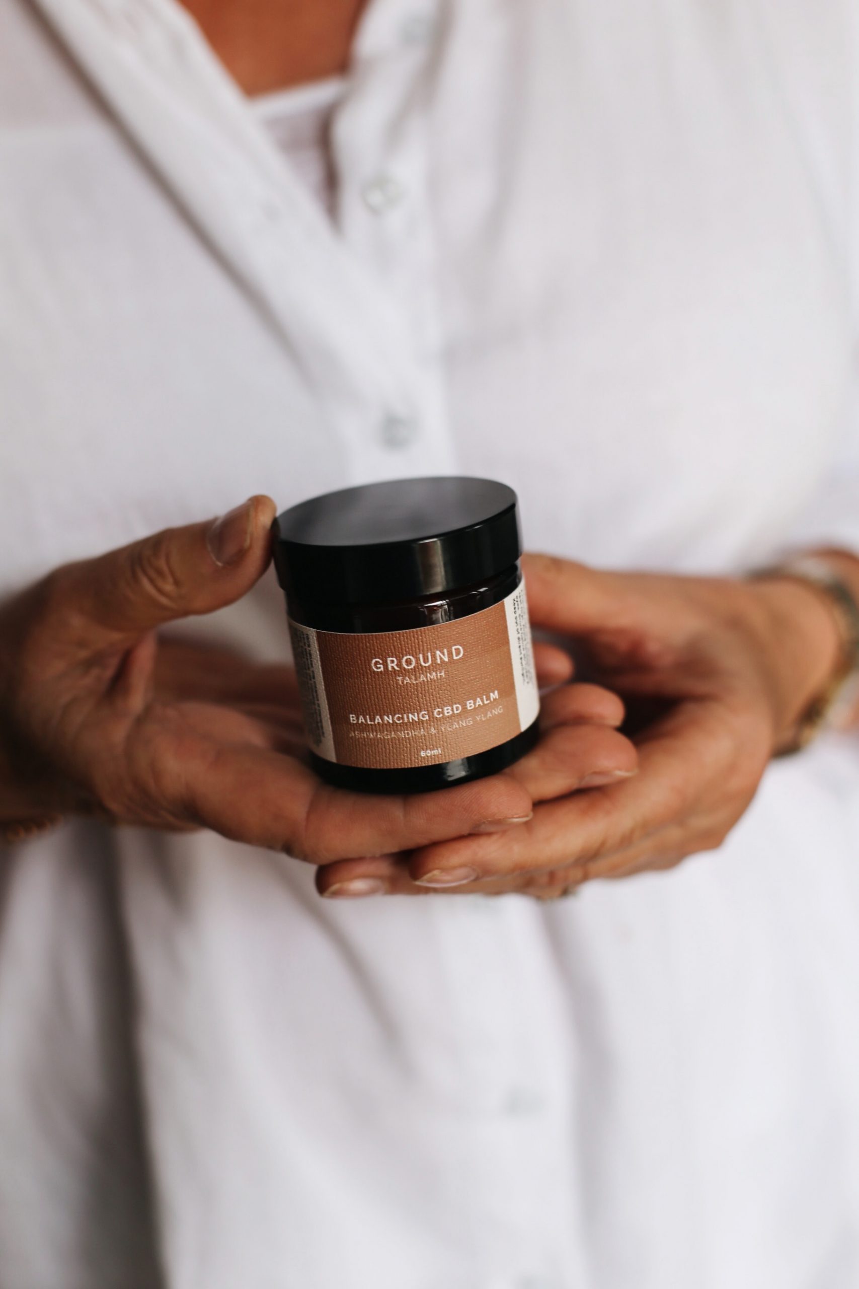 Menopause: A jar of ground CBD balm in a person's hands