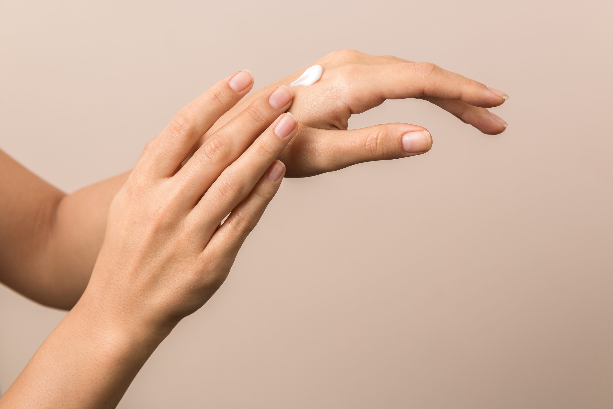 A hand rubbing cream into the back of another hand