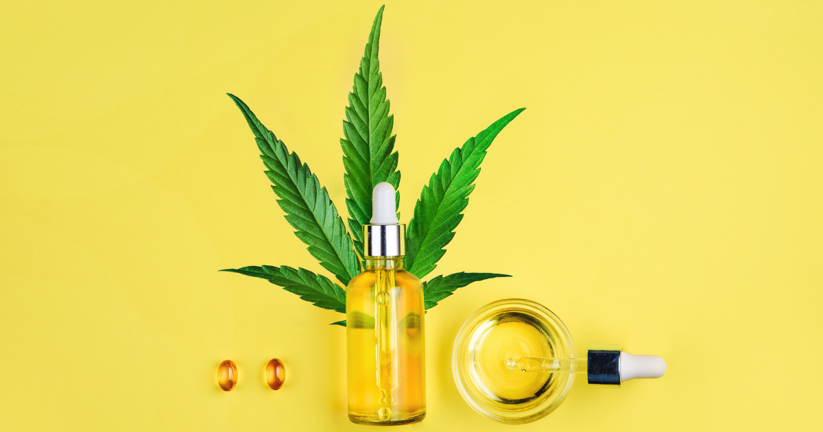 Juicyfields: A cannabis leaf with a small bottle of oil, two capsules, a jar and a dropper of oil on a yellow background