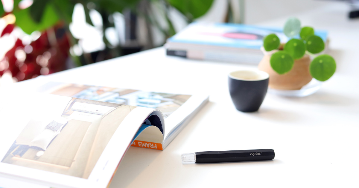 Kanabo: A vape lying on a magazine with a cup of coffee nearby